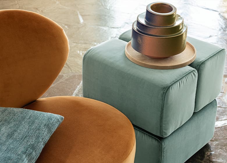 Ein orangener Sessel und ein grüner Pouf.