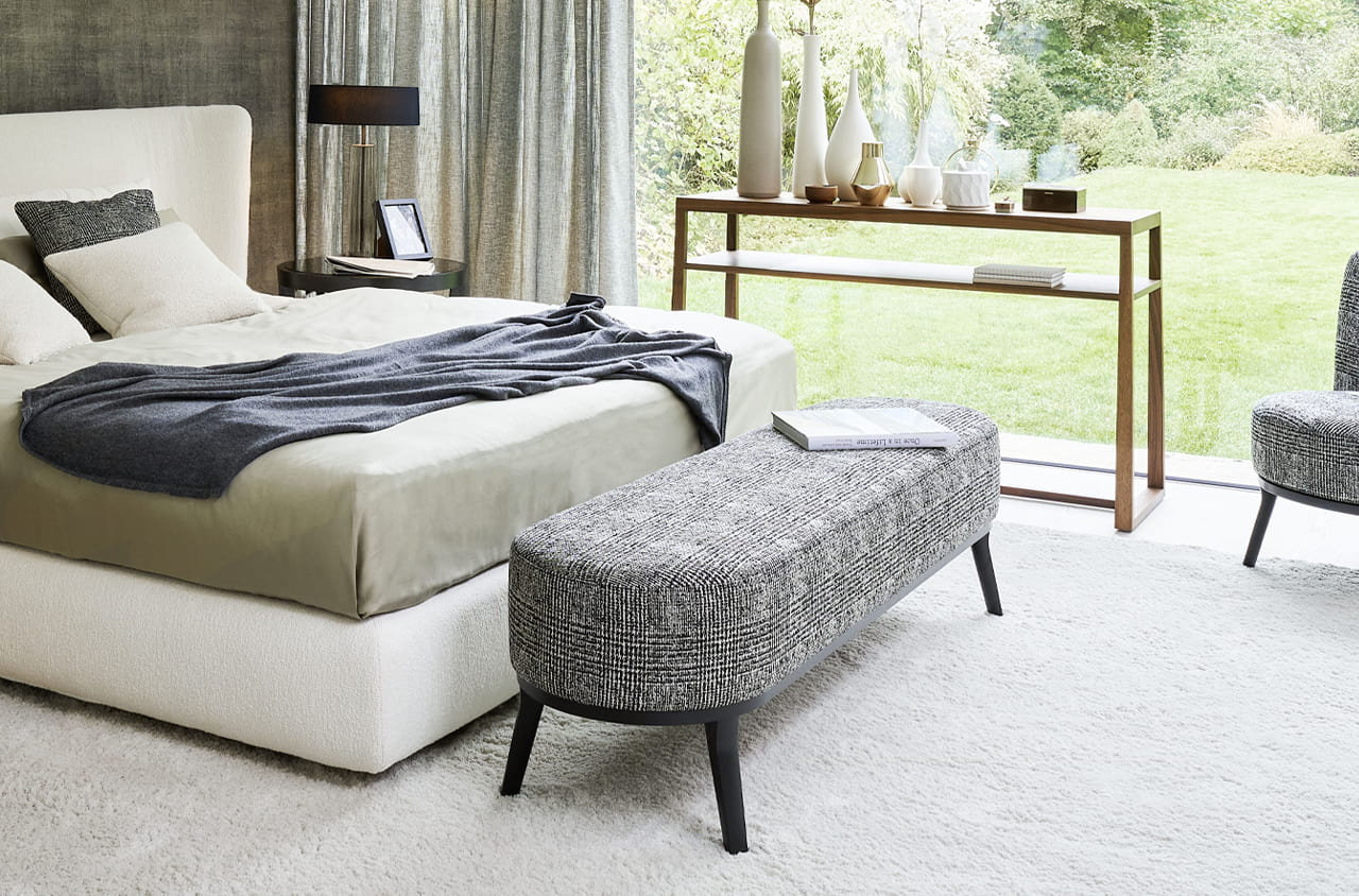 Graue Polsterbank vorm Bett