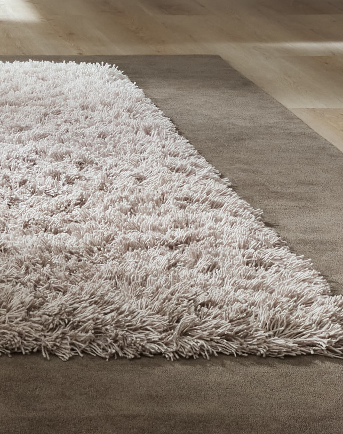 Nahaufnahme von einem Teppichdesign, das viereckig ist, der Rand ist braun und tiefer florig und die Mittegrau und hat einen höheren Flor