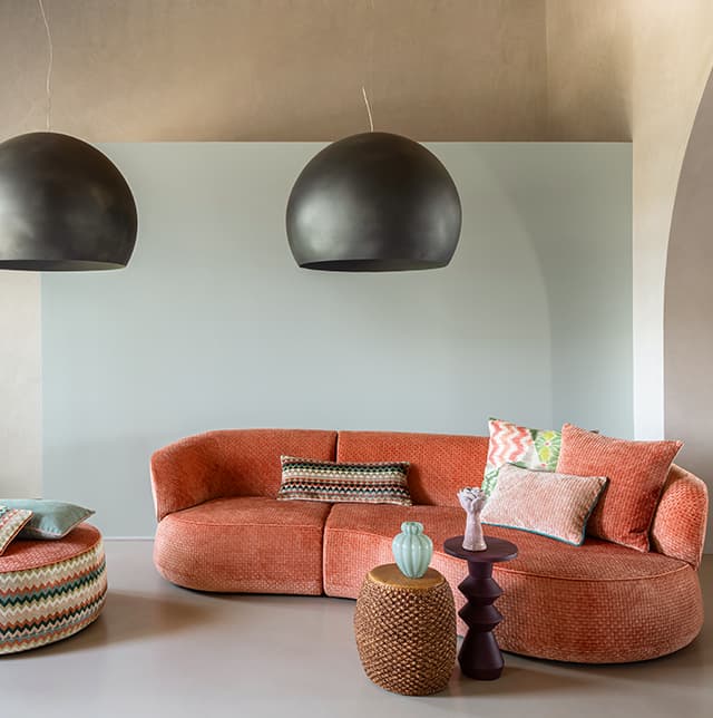Ein orangenes Sofa und ein Pouf mit grafischem Muster.