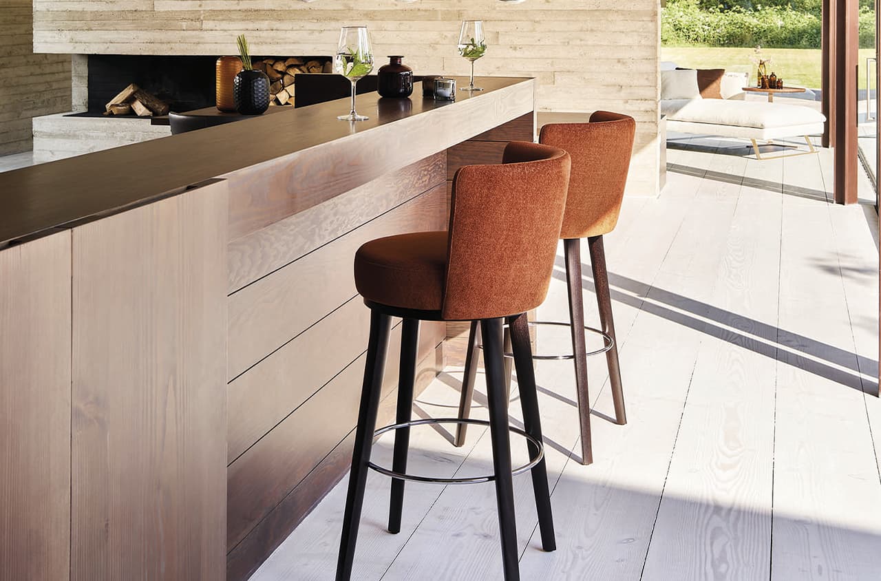 Zwei braune Barstühle vor einer Bar in einem Raum mit vielen Holzelementen