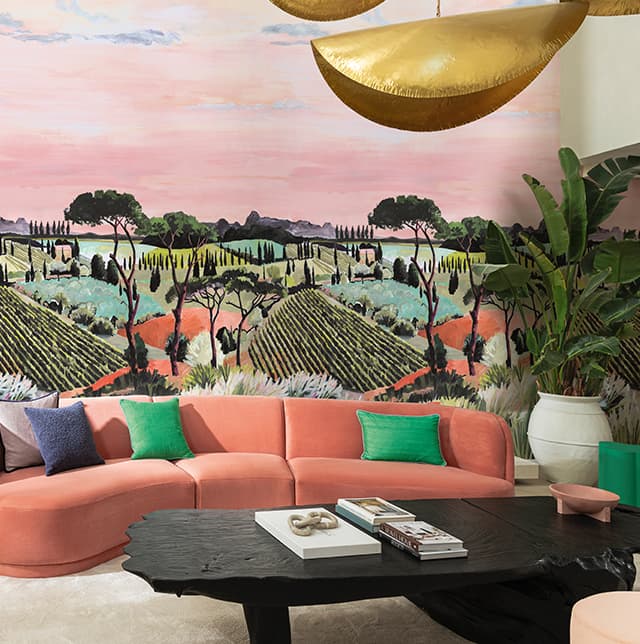 Ein orangenes Sofa mit bunten Kissen und einer Printtapete