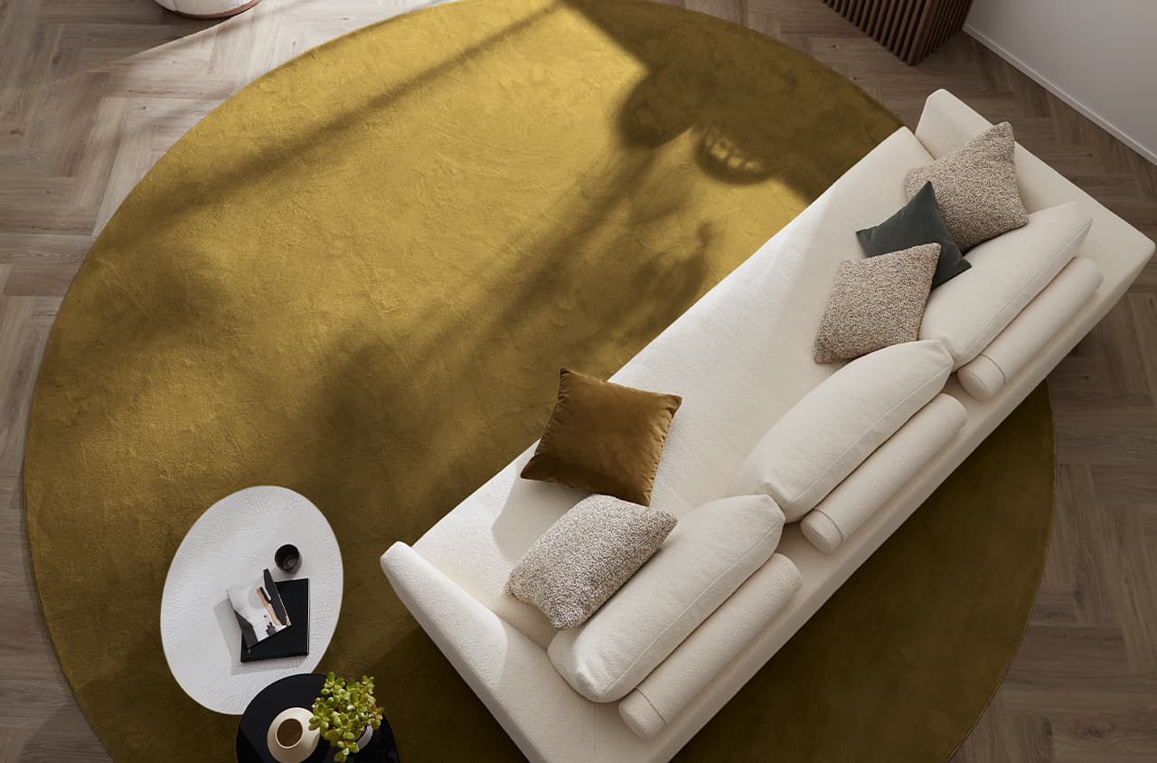 Teppich Glory in Senfgelb aus der Vogelperspektive fotografiert, auf dem Teppich ein weißes Sofa mit Kissen und ein Tisch
