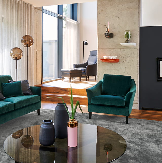 Grüner Polstersessel mit dazugehörigen Sofa im Wohnzimmer.
