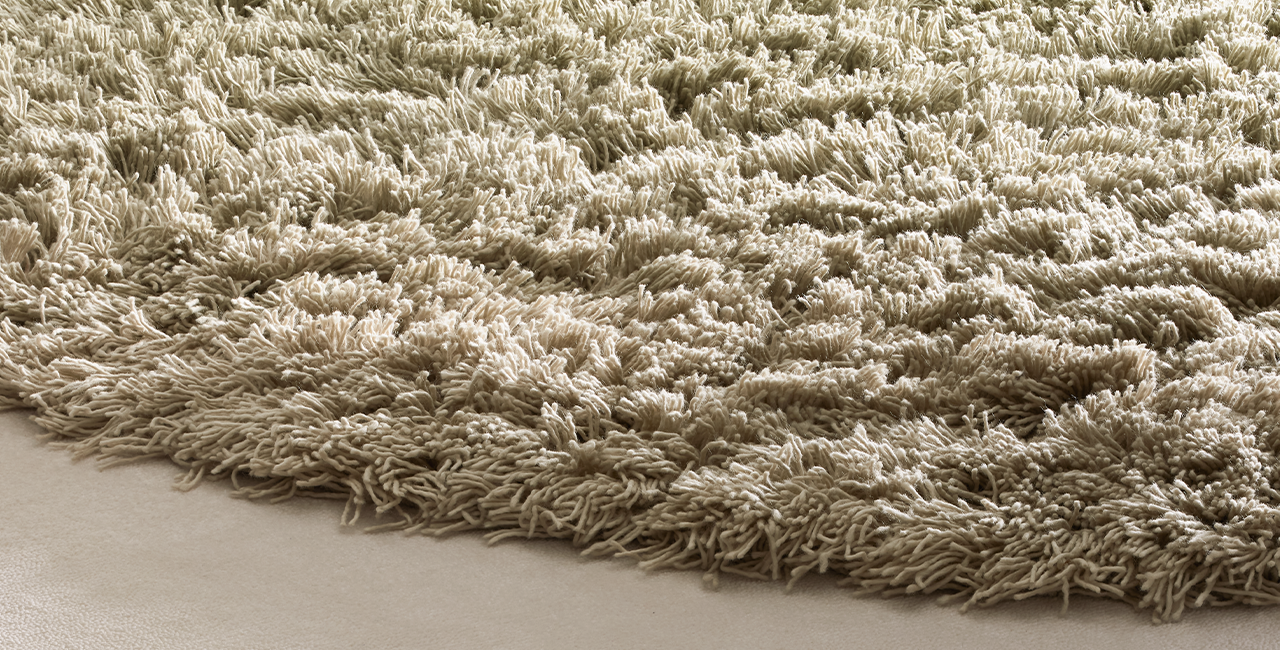 Nahaufnahme von einem quadratischen Teppichdesign, bei dem der Rand weiß/beige ist und tiefer florig und die Mitte ist rund, grün und hat einen höheren Flor