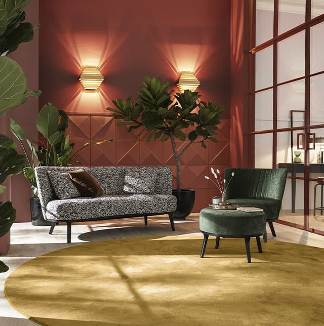 Ein graues Sofa und ein grüner Sessel in einem warmen Raum mit Orange- und Senf-Tönen