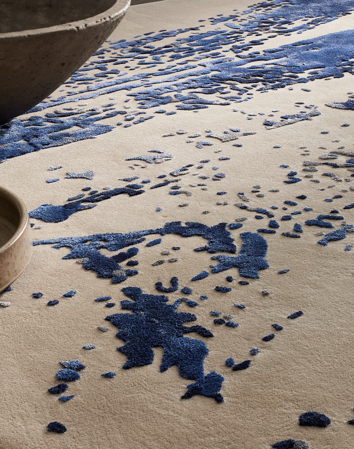 Teppich mit abstraktem Muster in Blau- und Grautönen auf hellem Grund. 