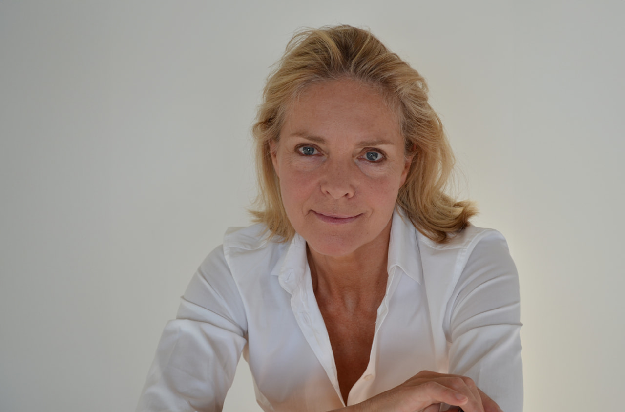 Portraitbild einer blonden Frau in einem weißem Hemd. Sie lächelt freundlich in die Kamera.