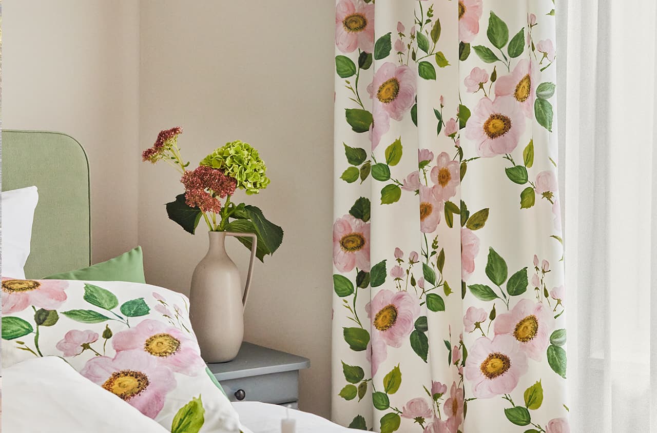 Blumenmuster auf einem Kissen und einer Gardine im Schlafzimmer