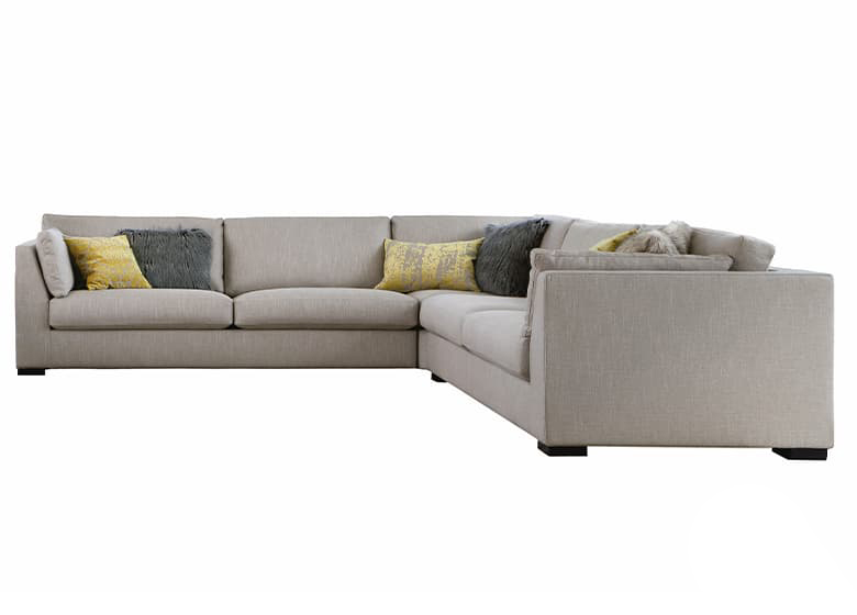 Freisteller eines beigen Sofas mit einem Eckteil und mehreren Deko-Kissen in graun und gelb. 