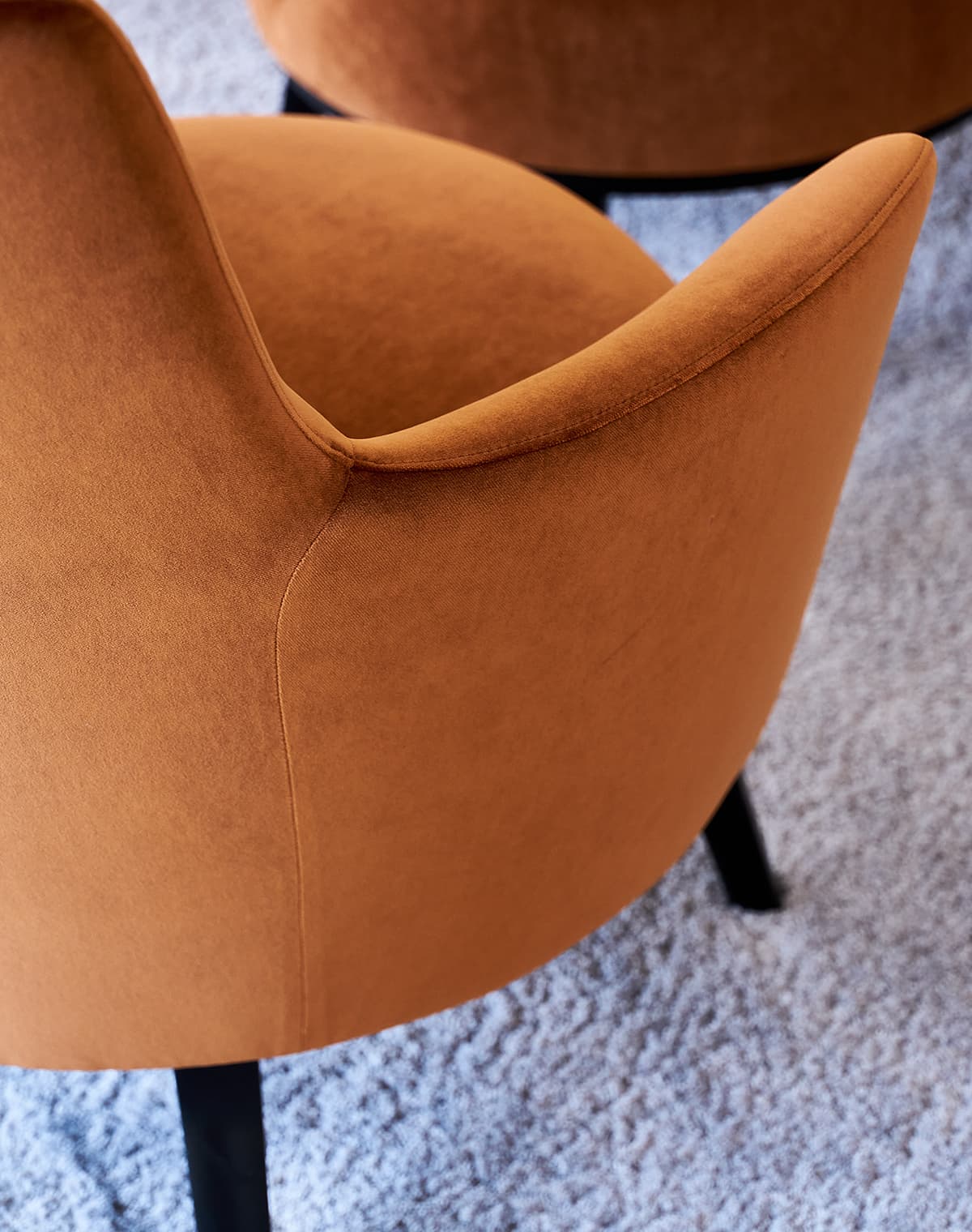 Sessel Polo Cocktail in orange mit schwarzen Füßen auf einem grauen Teppich