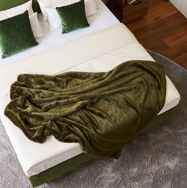Plaid Soft Whisper in grün auf einem Bett