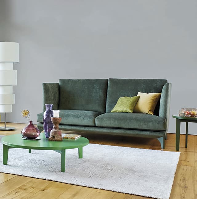 Grünes Sofa mit gelben Dekokissen in einem warmen Raum