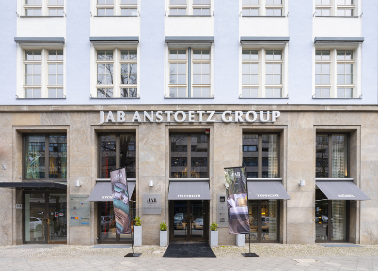 Außenaufnahme von einem Gebäude, vor dem Eingang hängt der große Schriftzug JAB ANSTOETZ Group