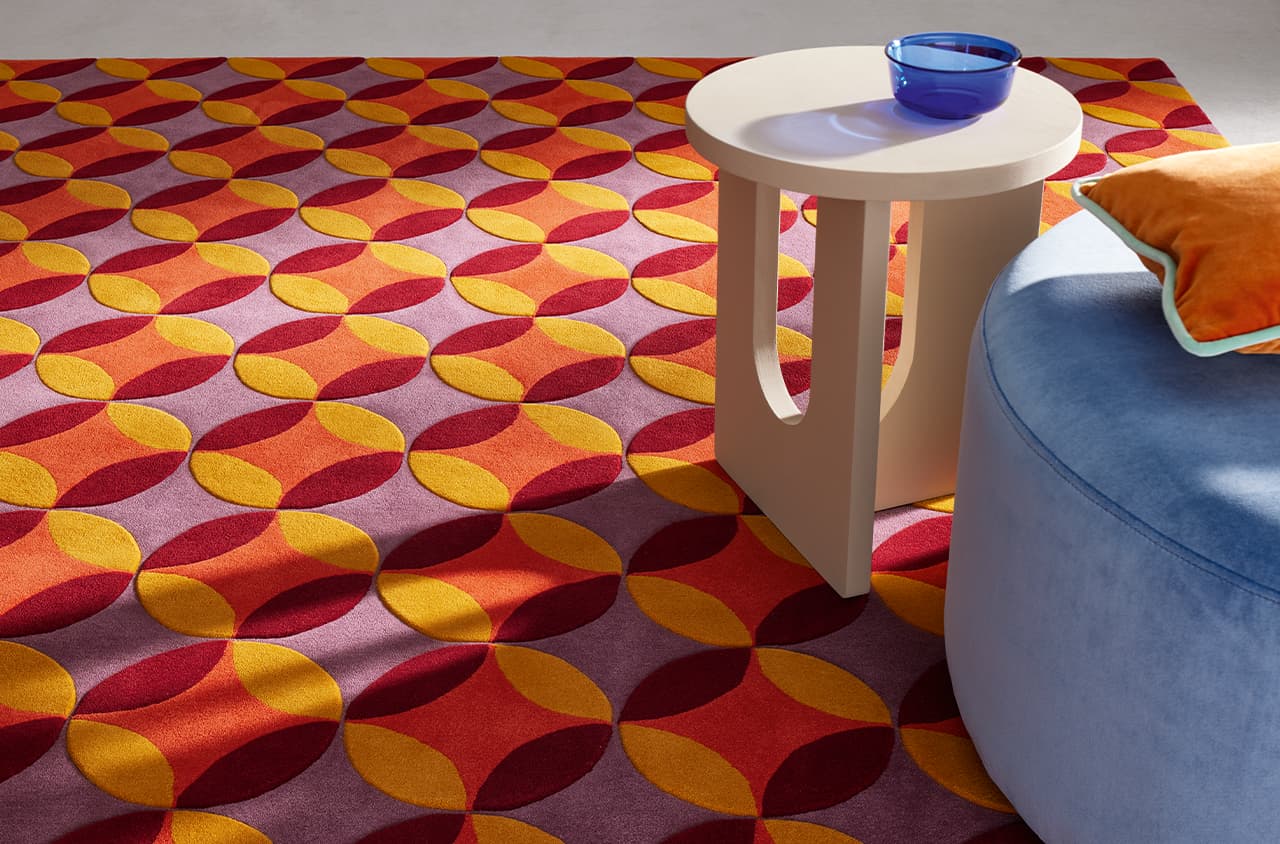 Teppich Be United Multi mit einem blauen Hocker und weißen Tisch von relativ nahem fotografiert