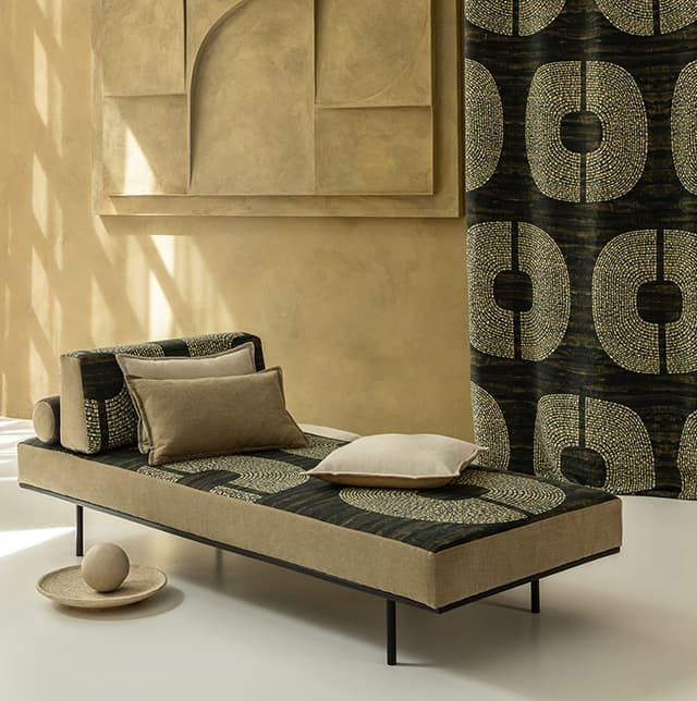 Sofa in natürlichen Farbtönen mit geometrischem Muster, 3 Kissen und ein Vorhang mit dem selben geometrischen Muster.