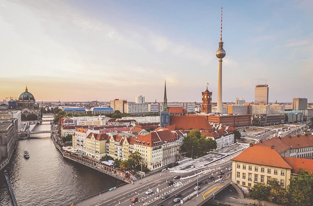 Drohnenfoto von Berlin. Man sieht viele Gebäude und im Hintergrund den Fernsehturm.