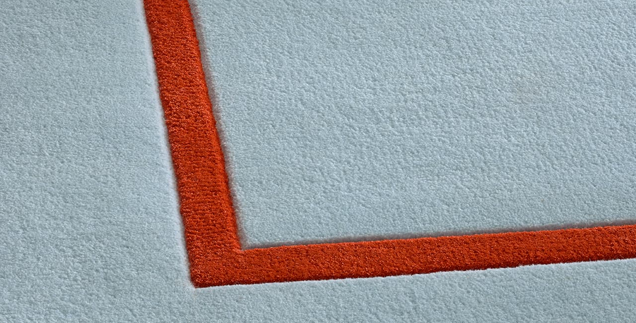 Teppichdesign in hellblau mit einem schmalen roten Randstreifen