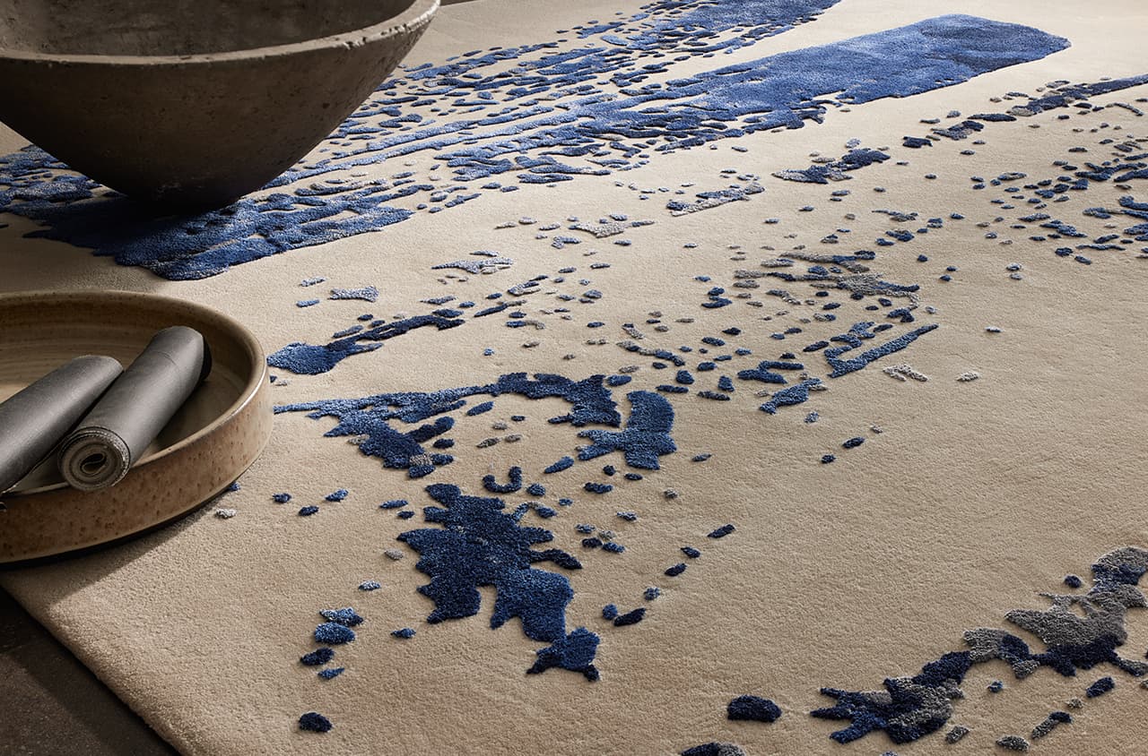 Teppich mit abstraktem Muster in Blau- und Grautönen auf hellem Grund.