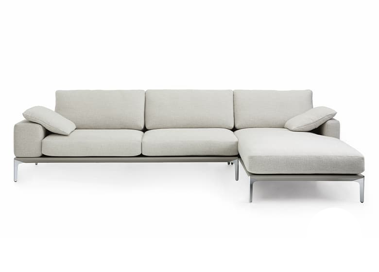 Freisteller eines weißen Sofas mit einem Longchair und zwei weiteren Sitzflächen. Auf den Armlehnen liegen Kissen.