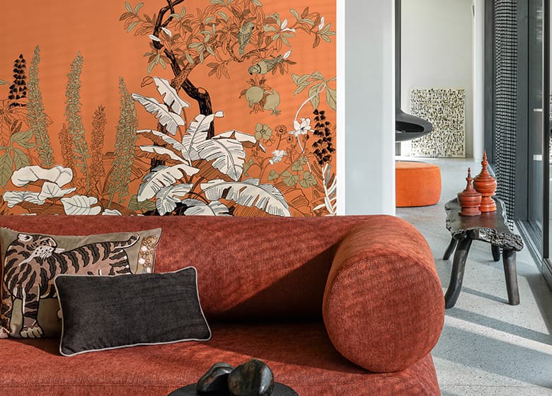 Rotes Sofa vor orangener Tapete mit floralem Motiv