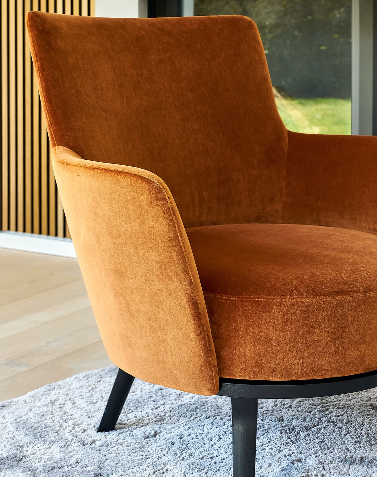 Sessel Polo Cocktail mit Armlehnen in orange und schwarzen Füßen auf einem grauen Teppich