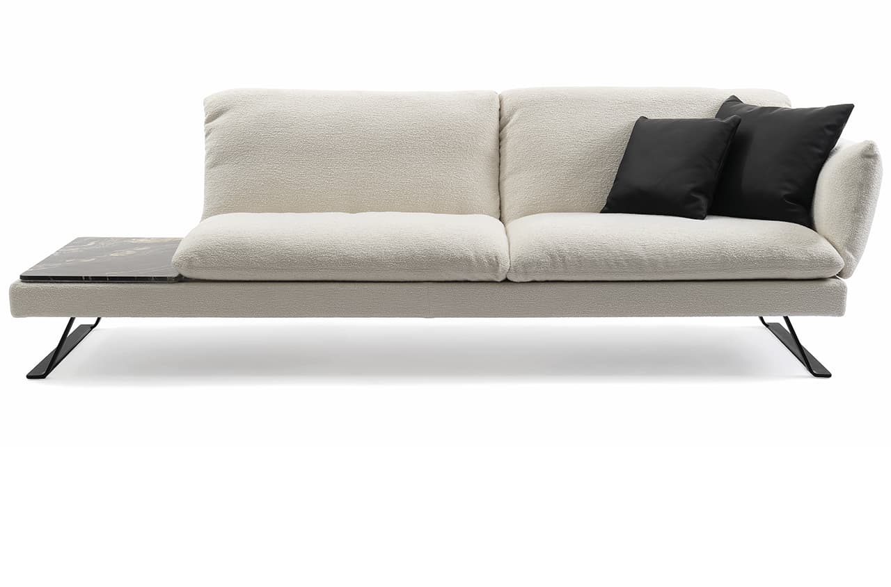 Freisteller eines weißen Sofas mit zwei schwarzen Deko-Kissen. An dem Sofa ist ein Abstelltisch angebrachtt.