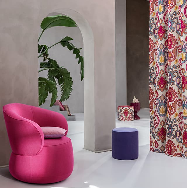 Ein pinker Sessel, ein lila Pouf und ein Pouf und Vorhang mit dem selben Muster