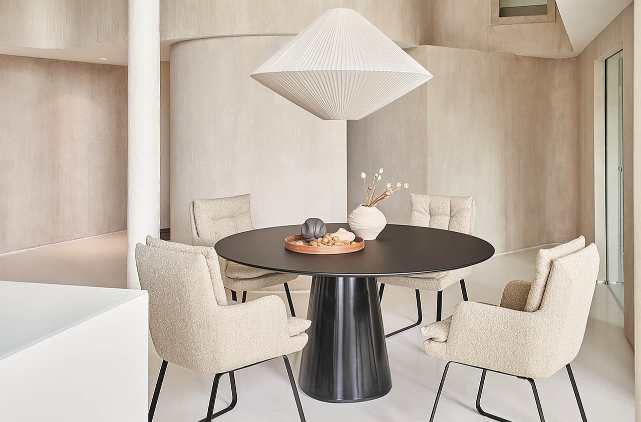 Soulmate Dining Stühle in beige um den schwarzen Roxy Esstisch rumgestellt in einem hellen raum und über dem Tisch hängt eine helle Leuchte