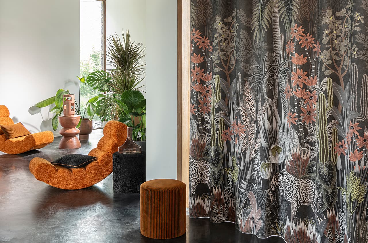 2 orangene Sessel und ein orangener Pouf und ein Vorhang mir floralem Print