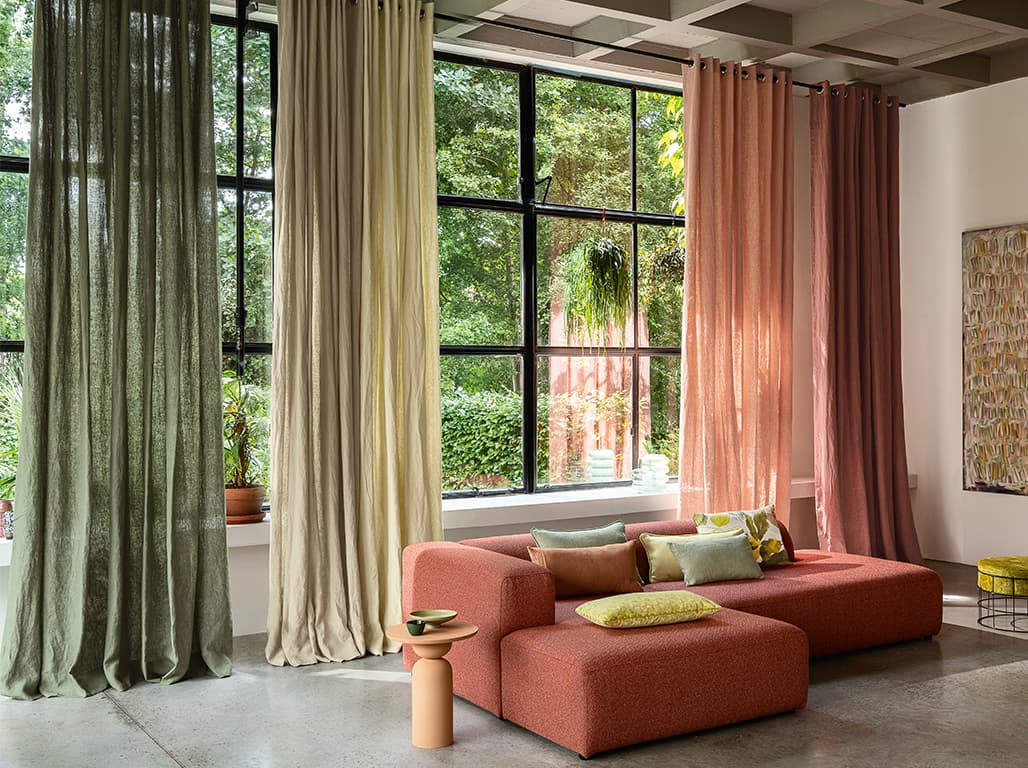 Orangenes Sofa und Vorhänge am Fenster in rot, orange, grün und gelb.
