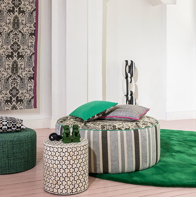 Poufs und Kissen mit verschiedenen Mustern und ein grüner Teppich.