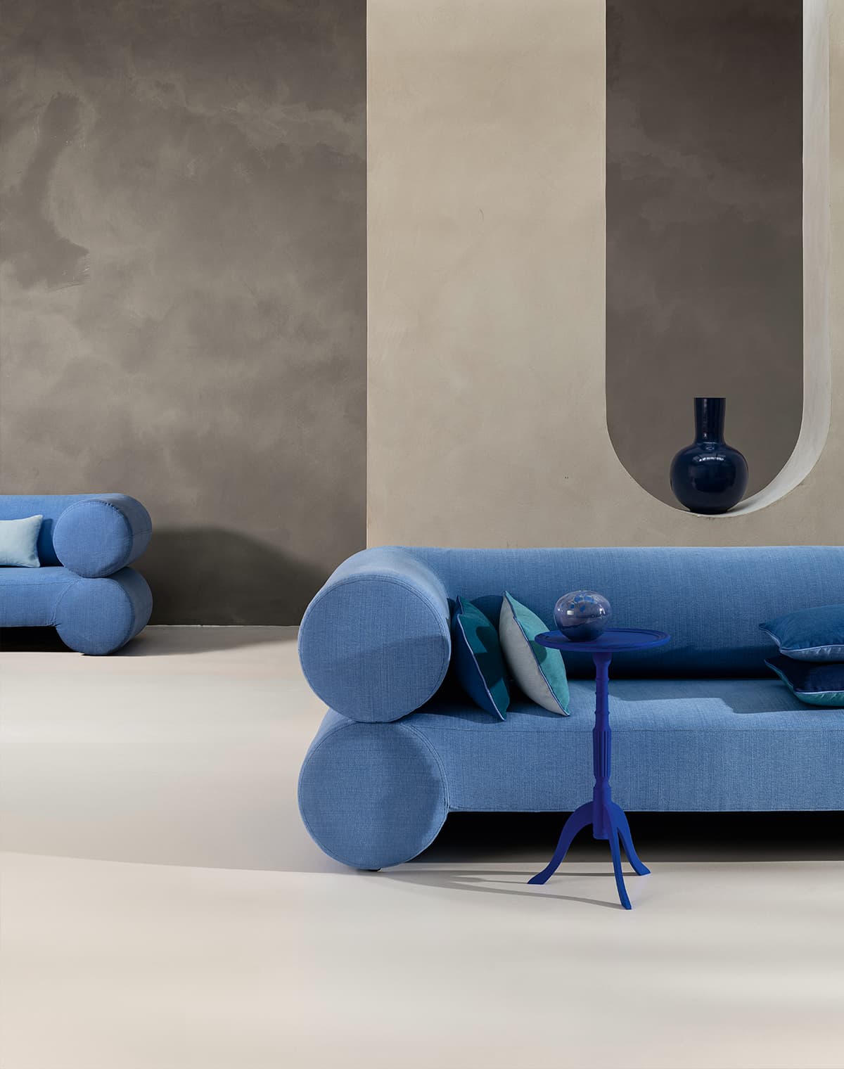 Zwei blaue Sofas mit blauen Kissen, ein blauer Beisteltisch mit blauer Deko und eine blaue Vase.